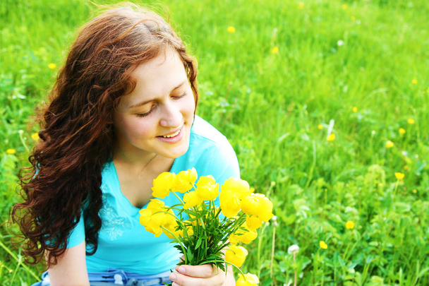 portrait of beautiful redhead woman with a bouquet of spring fresh yellow flowers. - Фото, зображення