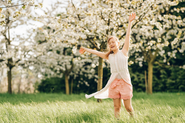 Küçük bahar çiçek açan bahçede oynayan kız çocuk - Fotoğraf, Görsel