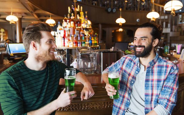 male friends drinking green beer at bar or pub - Foto, afbeelding