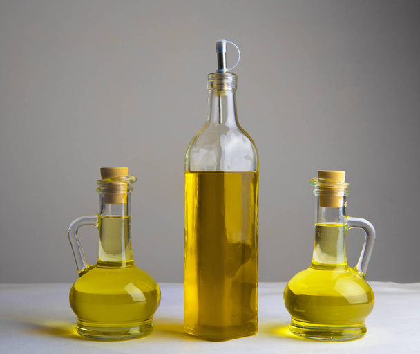 three olive oil glass transparent bottles  with corks on white table on kitchen  - Photo, image