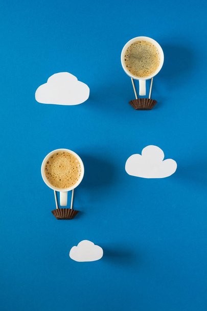Air balloon from cups of espresso with paper clouds. Paper art style or craft. - Foto, Imagem