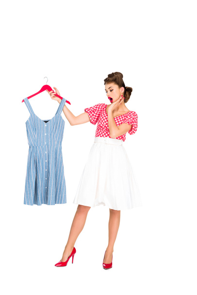 shocked stylish woman in retro clothing looking at dress on hanger in hand isolated on white - Fotografie, Obrázek