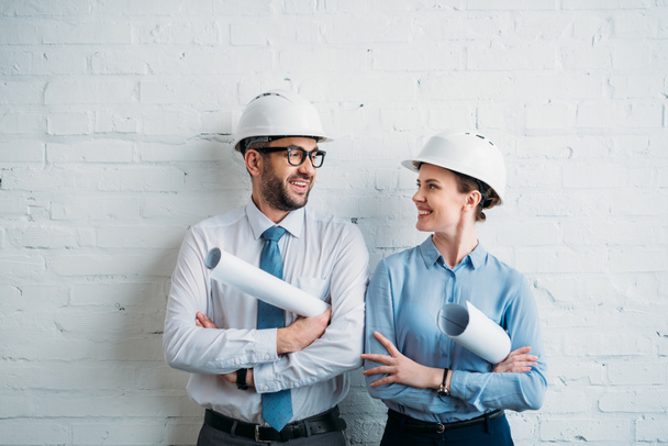 architects in hard hats standing in front of white brick wall with blueprints - Photo, Image