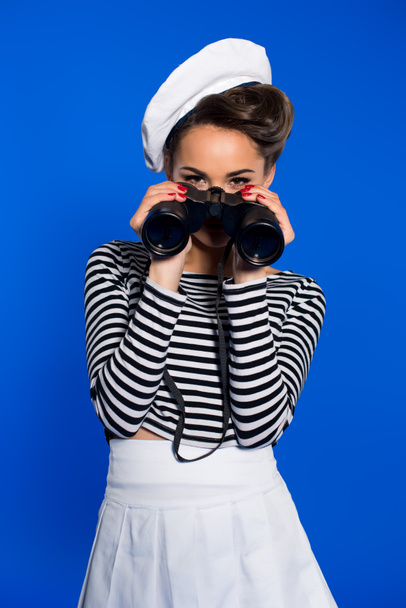 attractive young woman in retro clothing with binoculars isolated on blue - Photo, Image