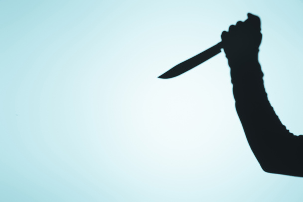 spooky σκιά του προσώπου που κρατάει το μαχαίρι στο χέρι με μπλε - Φωτογραφία, εικόνα