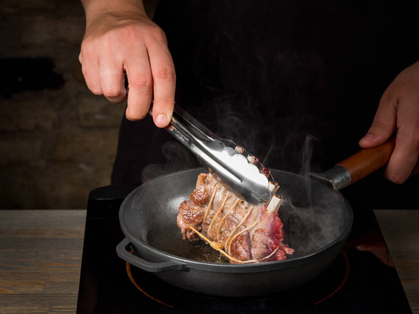 close-up of male hands grilled Beef Ribs on metal frying pan - Φωτογραφία, εικόνα
