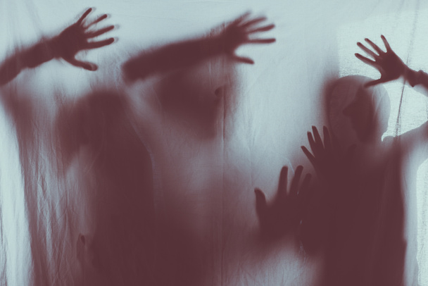 silhuetas assustadoras desfocadas de pessoas tocando vidro fosco com as mãos
 - Foto, Imagem