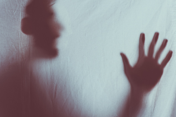 eng wazig silhouet van onherkenbaar persoon schreeuwen achter de sluier - Foto, afbeelding
