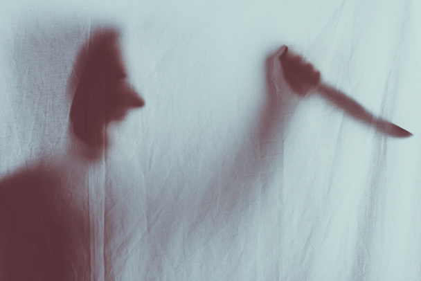 silueta borrosa miedo de la persona gritando y sosteniendo cuchillo detrás del velo
  - Foto, Imagen