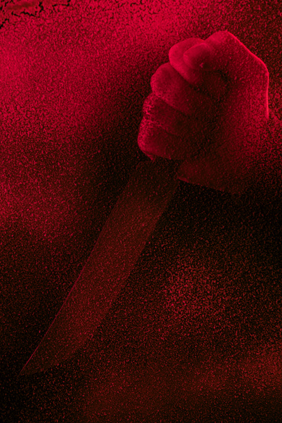 abgeschnittene Aufnahme menschlicher Hand mit Messer in Rotlicht mit Pannen  - Foto, Bild
