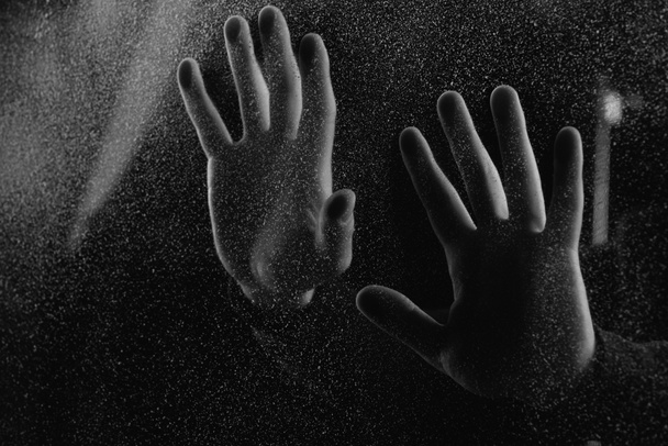 abgeschnittene Aufnahme einer Person, die in der Dunkelheit Milchglas mit Handflächen berührt   - Foto, Bild