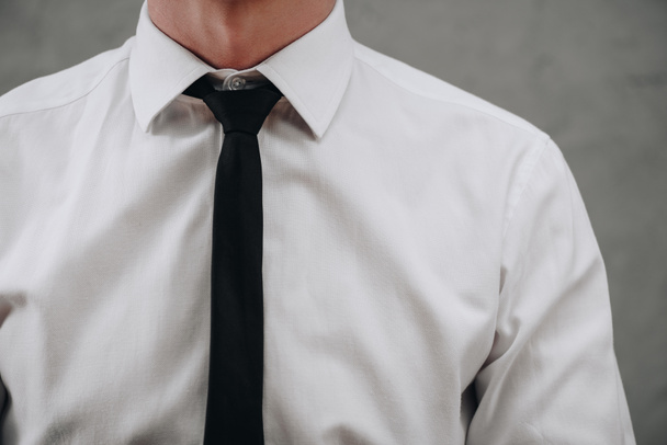 cropped shot of businessman in white shirt and black necktie on grey - 写真・画像