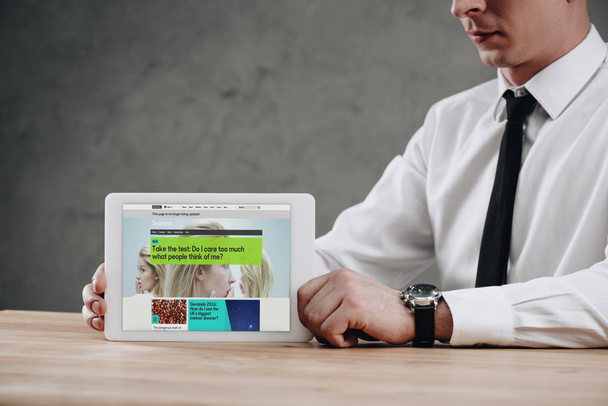 cropped shot of businessman holding digital tablet with BBC website on screen - Foto, Imagen