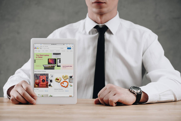 Oříznout záběr podnikatel drží digitální tablet s ebay stránky na obrazovce  - Fotografie, Obrázek