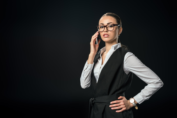 young beautiful businesswoman talking on smartphone, isolated on black - Foto, Bild