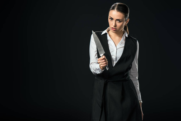 young beautiful businesswoman holding knife, isolated on black - 写真・画像