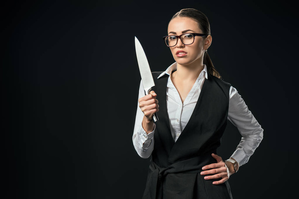 young confident businesswoman holding knife, isolated on black - Photo, Image