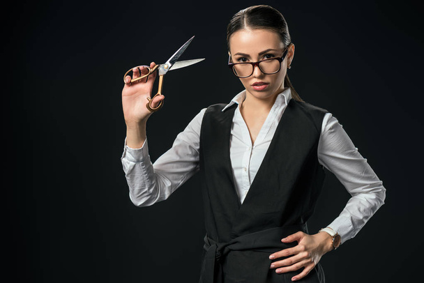 young businesswoman holding scissors, isolated on black - Photo, Image
