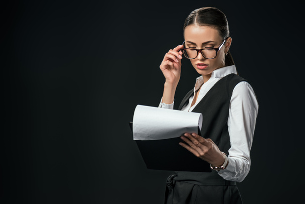 confident businesswoman holding documents on clipboard, isolated on black - Photo, image