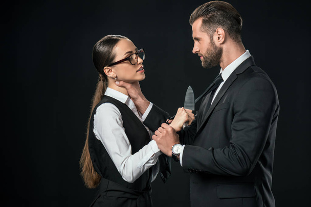 business partners holding knife and quarreling isolated on black - Фото, зображення