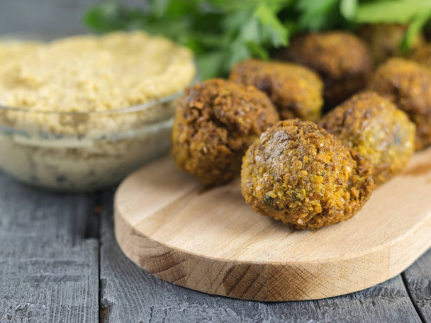 Pasta tahina in a glass bowl and falafel on a cutting Board on a wooden table. - Zdjęcie, obraz
