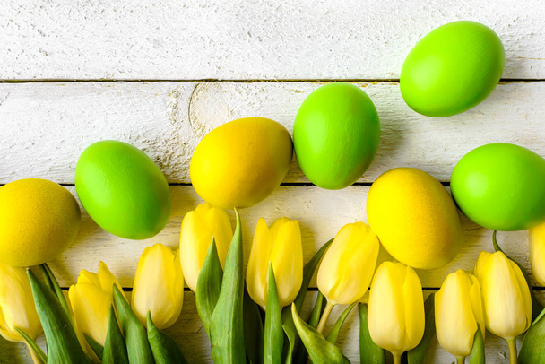 Wooden background with spring easter eggs and tulips on table, top view - Foto, Imagen