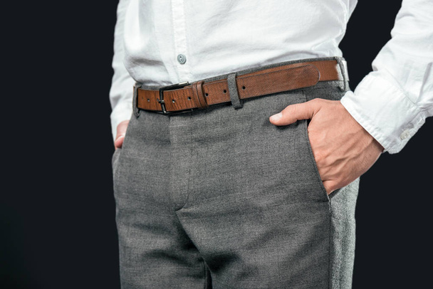 cropped view of businessman with hands in pockets, isolated on black - Fotografie, Obrázek