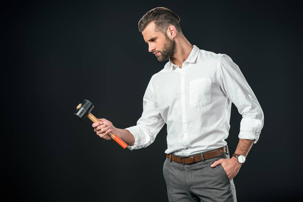 handsome businessman in white shirt holding hammer, isolated on black - Photo, image