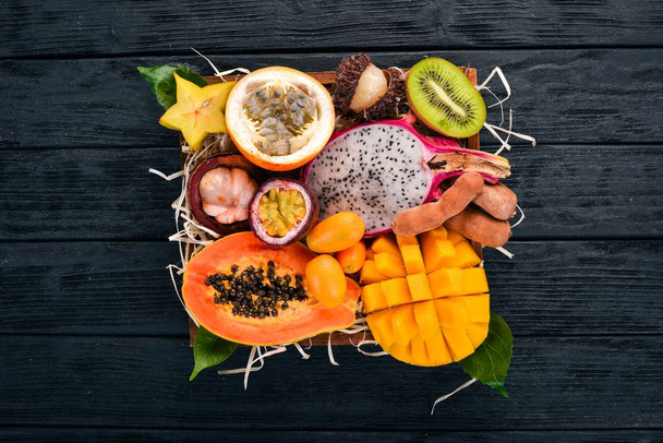 Fruit dragon, papaya, maracuya, kiwi, mango and granadilla in a wooden box. Fresh Tropical Fruits. On a wooden background. Top view. Copy space. - Foto, afbeelding