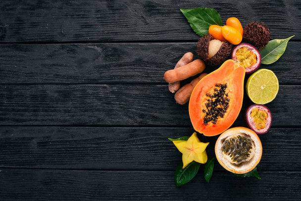 Papaya, kumquat, granadilla, maracuya, carambola. Tropical Fruits. On a wooden background. Top view. Copy space. - Foto, imagen