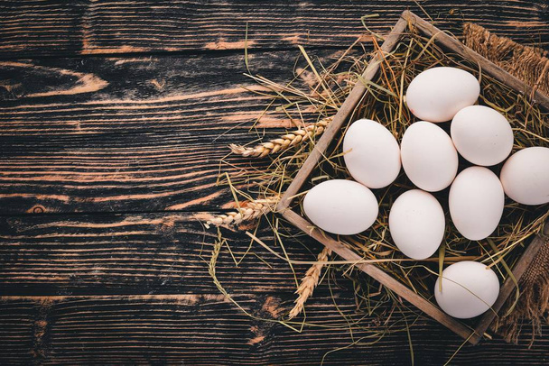 Chicken raw eggs in a wooden basket. On a wooden background. Top view. Copy space. - Photo, Image