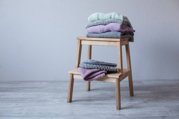 Stack of cozy knitted clothes on a wooden ladder. - Fotografie, Obrázek