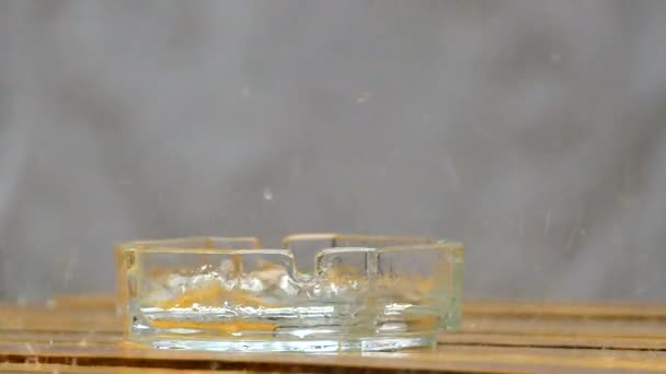 Druppels regenwater verslaan tegen de asbak. Slow motion. - Video