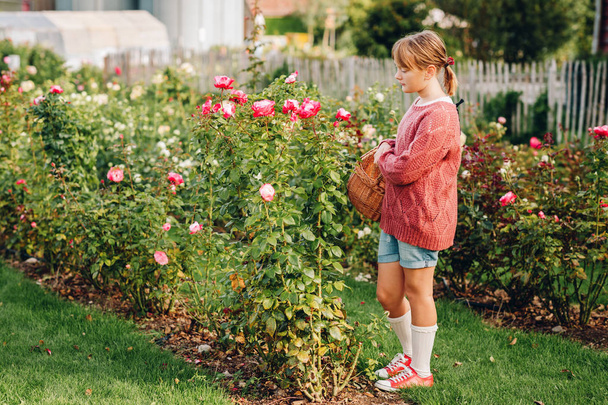 Маленька дівчинка грає в красивому трояндовому саду
 - Фото, зображення