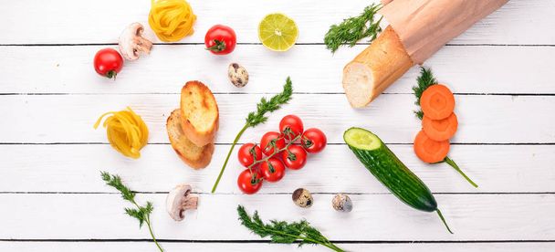 Essen. Baguette, Nudeln, Wachteleier, frisches Gemüse. auf weißem Holzgrund. Ansicht von oben. Kopierraum. - Foto, Bild