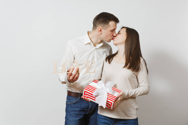 Cute couple in love. Man, woman with wooden word Love, present box with gift isolated on white background. For advertisement. St. Valentine's Day, International Women's Day, birthday, holiday concept. - Фото, изображение