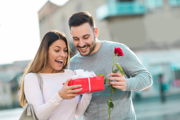 バレンタインの日に幸せなカップル。若い男は、若者に贈り物を与える  - 写真・画像