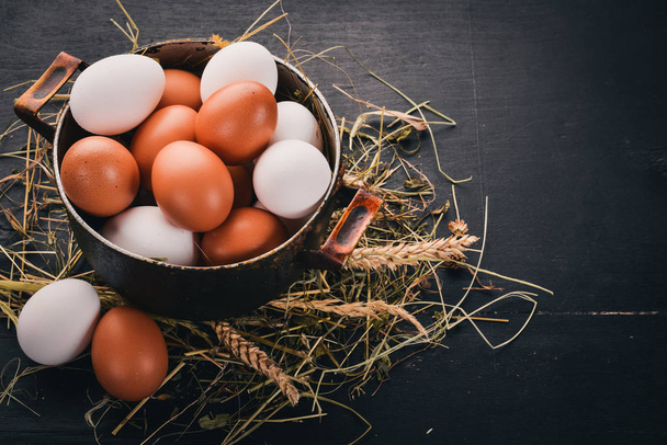 Chicken eggs in a metal saucepan. On a wooden background. Top view. Copy space. - Foto, imagen