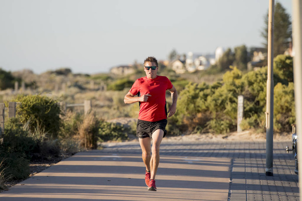 молодой привлекательный и счастливый спортивный бегун мужчина с хорошей физической формой и сильной здоровой тренировкой тела на бездорожье летом бег тренировки
 - Фото, изображение