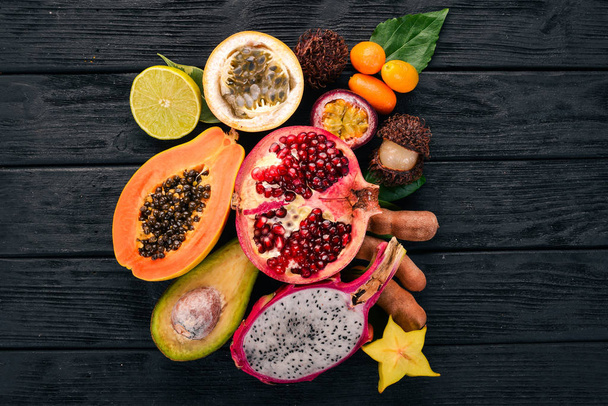 Dragon fruit, papaya, kumquat, hranadylla, avocado, passion fruit. Tropical Fruits. On a wooden background. Top view. Copy space. - Photo, image