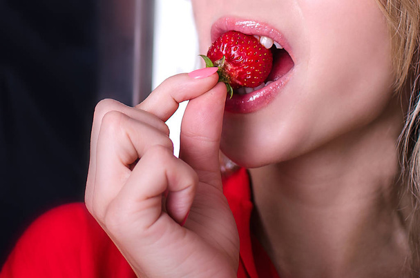 schöne Lippen, die eine Erdbeere halten - Foto, Bild