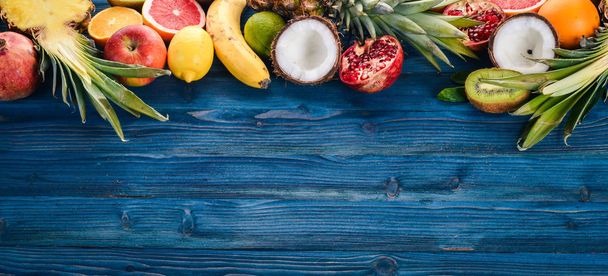 Fresh Tropical Fruits. Pineapple, coconut, kiwi, orange, pomegranate, grapefruit. On a wooden background. Top view. Free space for text. - Fotó, kép