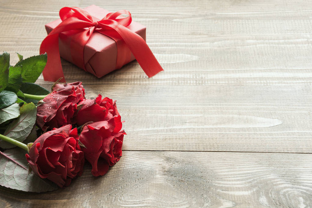 Bouquet red rose flowers and gift box on wooden table. Copy space. Close up. - Valokuva, kuva