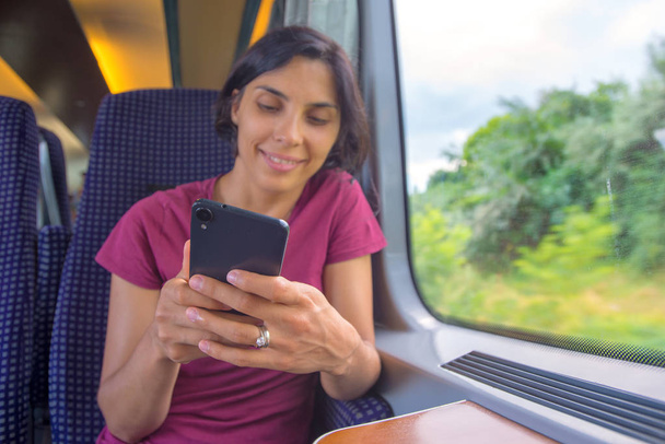 Nő textil neki telefonon, a vonaton utazás során - Fotó, kép