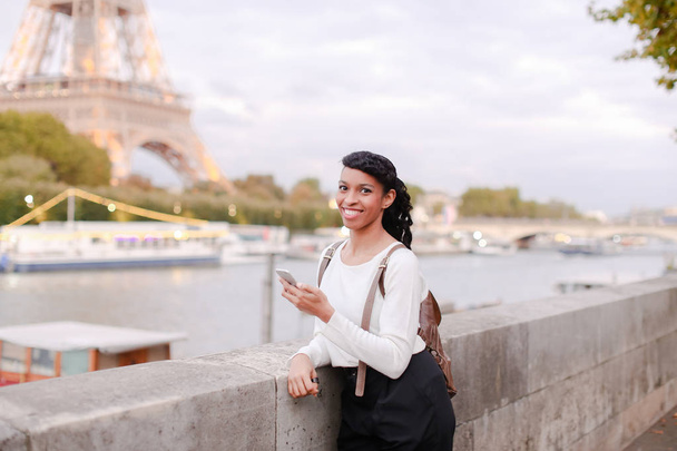 Улыбающаяся деловая женщина, стоящая на мосту и использующая смартфон
 - Фото, изображение