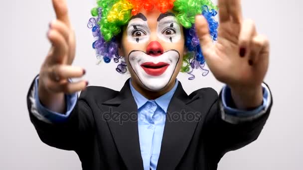 Клоун жінка в діловому костюмі і барвисті перуки роблять знаки зброї з рук
 - Кадри, відео