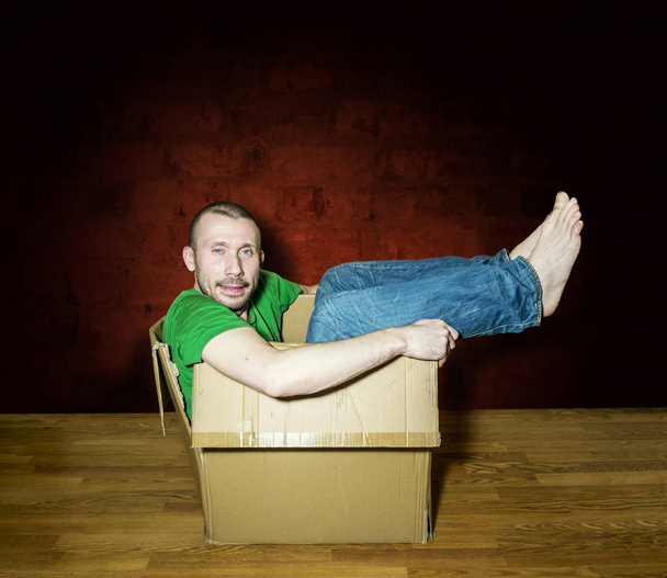 A man lies in a close box on brick wall background - Photo, Image