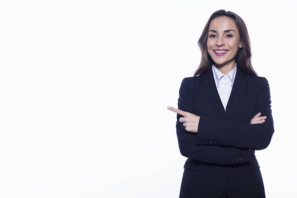 Confident beautiful smiling young business woman in suit on white background isolated pointing finger at empty field. - Zdjęcie, obraz