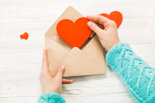 Kezét a lány szerelmes levél írása a Szent Valentin-nap. Kézi készítésű képeslapot piros szív alakú ábrát. Február 14-én ünnep ünnepe. Valentin nap fogalom-val másol hely - Fotó, kép