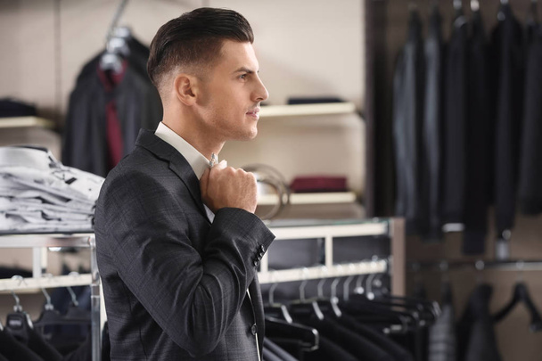 Handsome young man wearing suit in shop - Zdjęcie, obraz